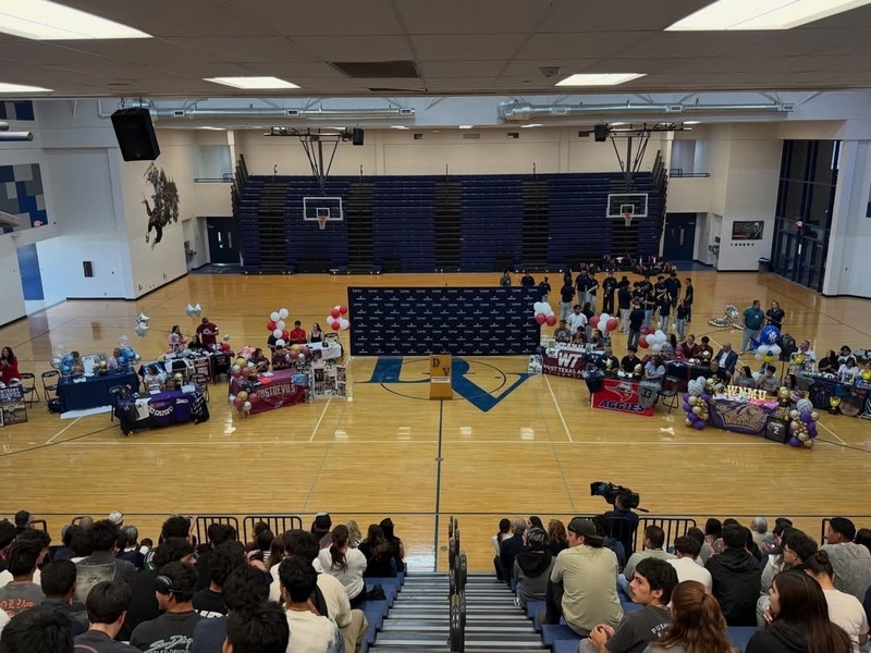 students sitting at tables with family singning letter of intent with colleges