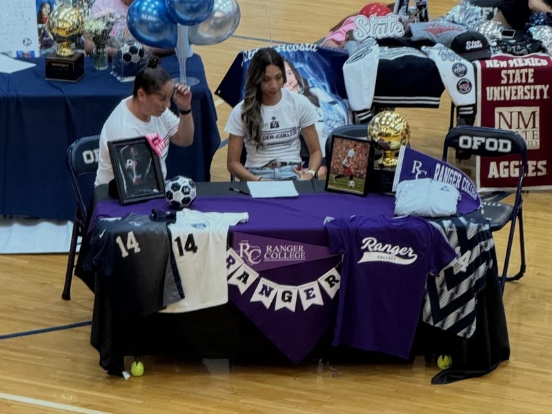 students sitting at tables with family singning letter of intent with colleges