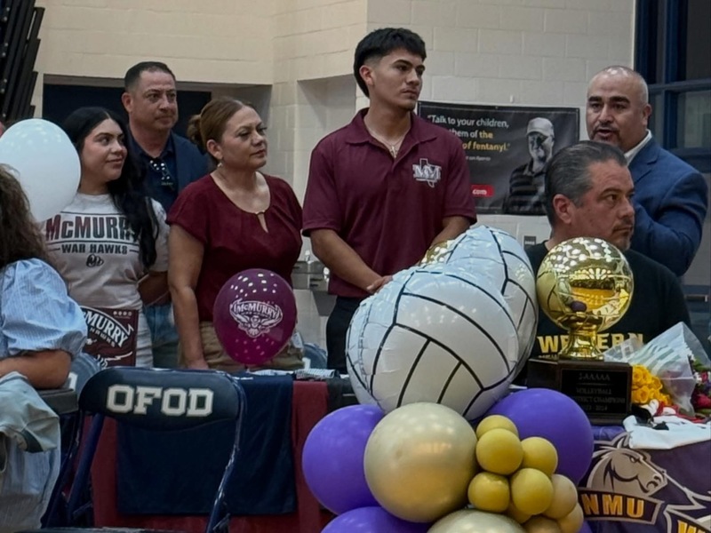students sitting at tables with family singning letter of intent with colleges