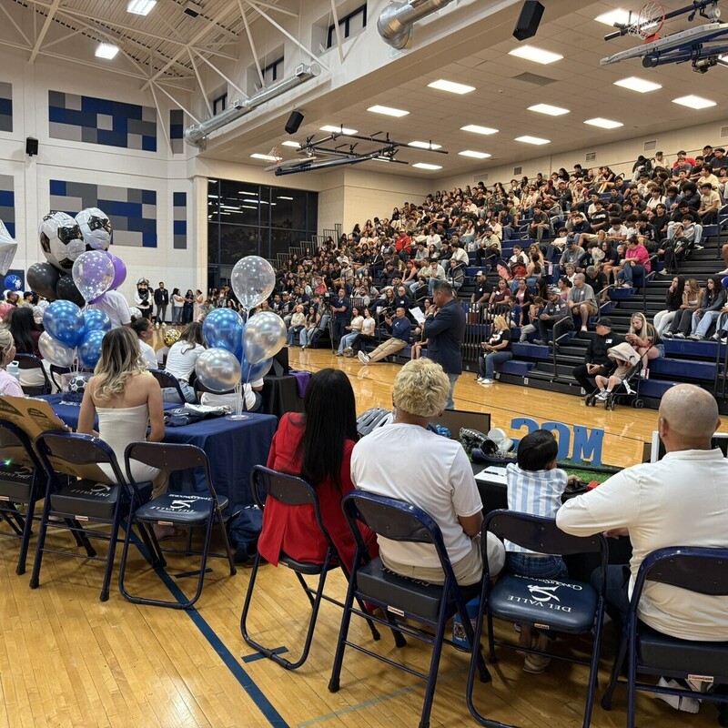 students sitting at tables with family singning letter of intent with colleges