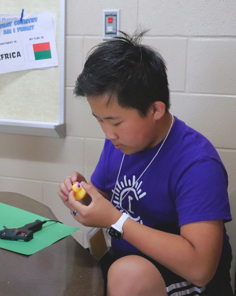 Boy with short black hair and a purple shirt putting eyes on a rubber duck