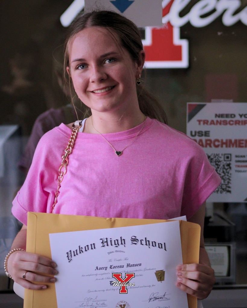 girl with a blonde pony tail and pink shirt holding up her white diploma and smiling