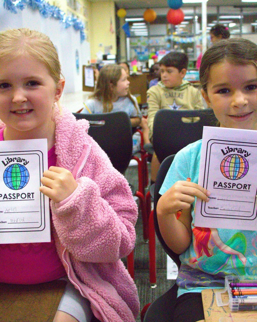two girls holding their drawings of their passports smiling
